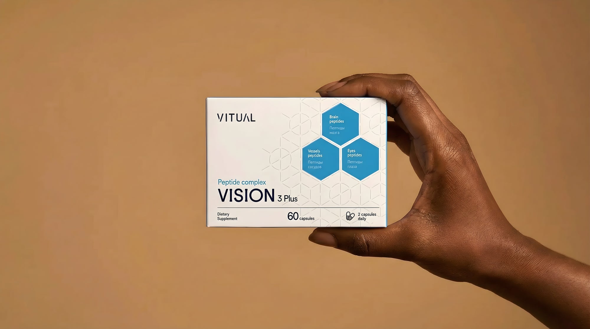 Hand holding a Vitual Vision Plus supplement package against a beige background
